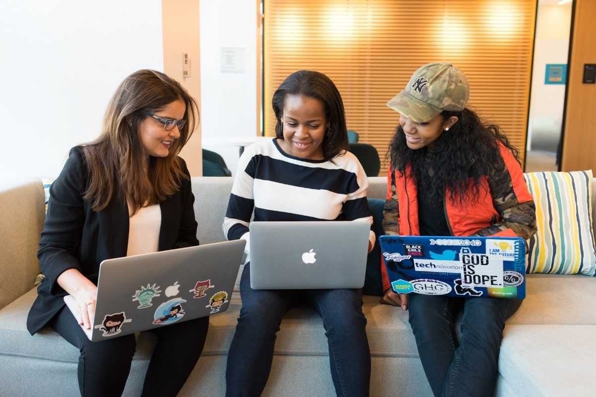 Picture of three women sitting on a couch, each with laptop computers to illustrate the true meaning of diversity in the tech field.