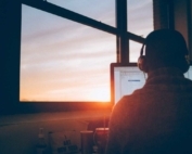 Software developer sitting next to a window facing the computer monitor.