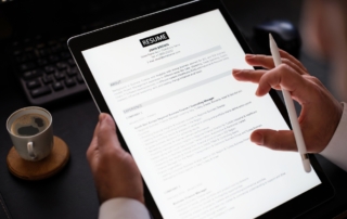 A close-up shot of a businessman reading a resume on his tablet.