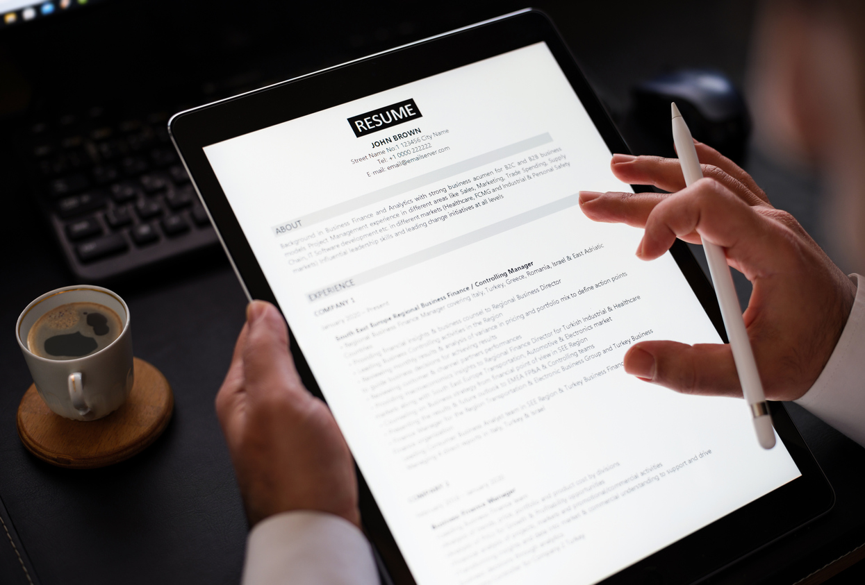A close-up shot of a businessman reading a resume on his tablet.