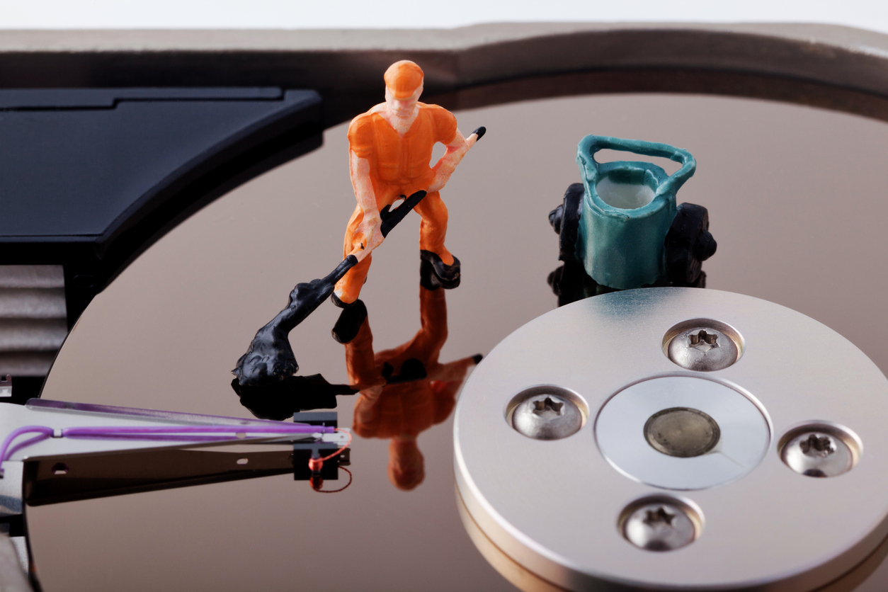 A minute toy worker cleaning up the hard drive he is standing on.